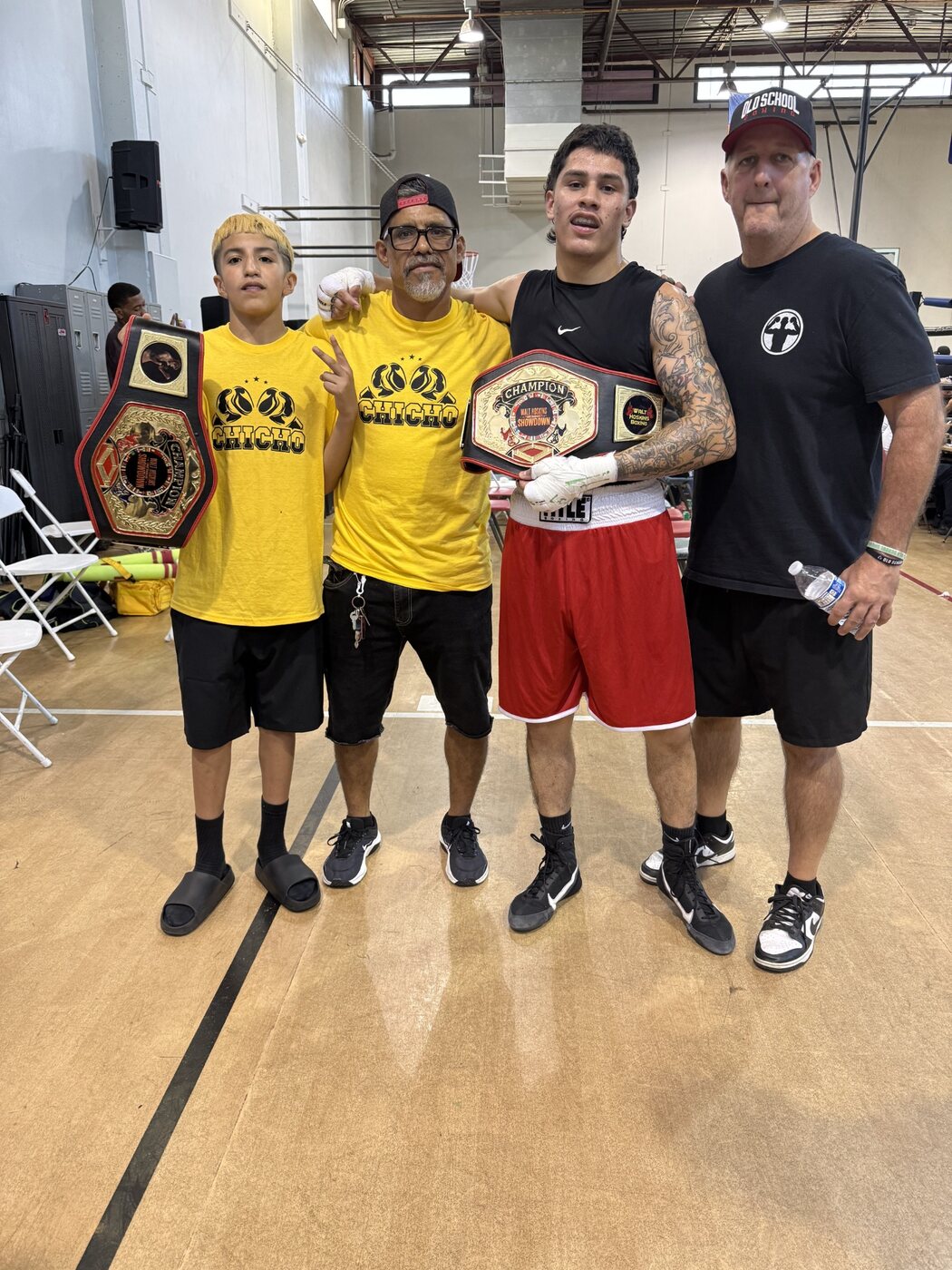 Chicho Rodriguez and Anthony Williams displaying their championship belts with coaches